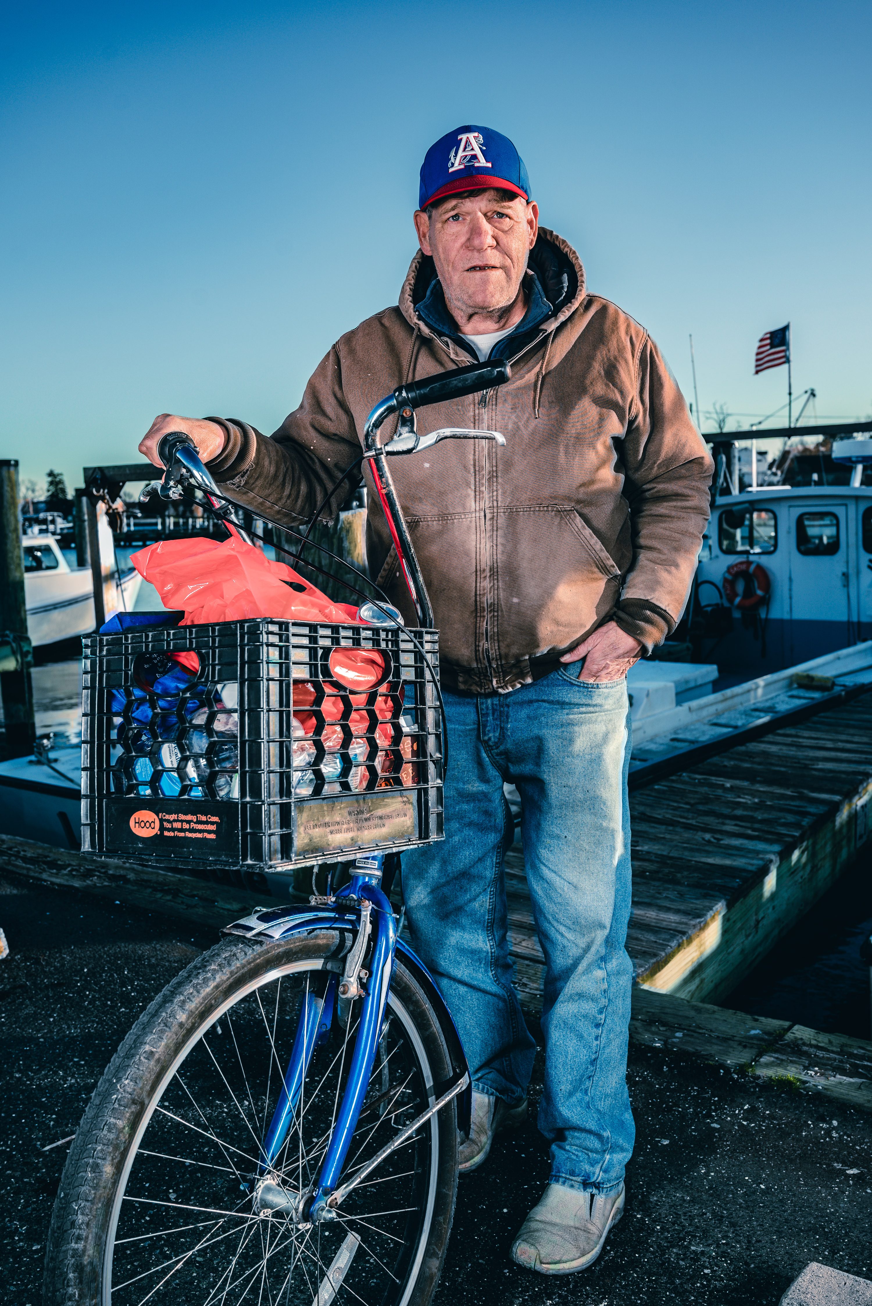 A waterman stands with his bicycle and milk crate on the dock.