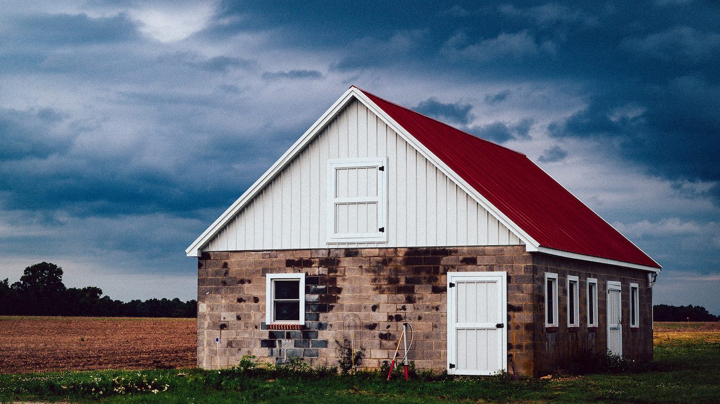 A red house sits alone in an open field.