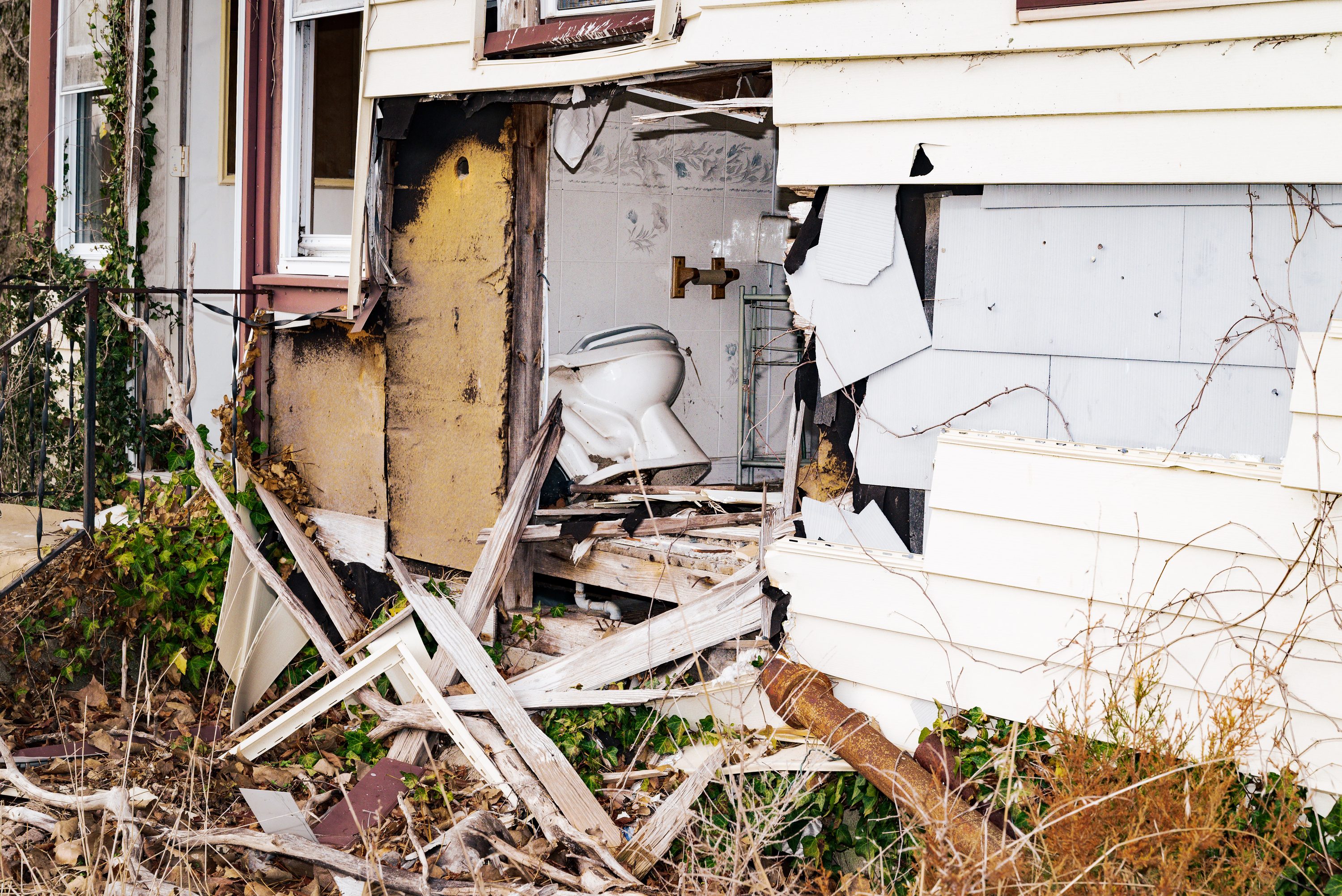 A toilet sits outdoors among the remains of a demolished house.