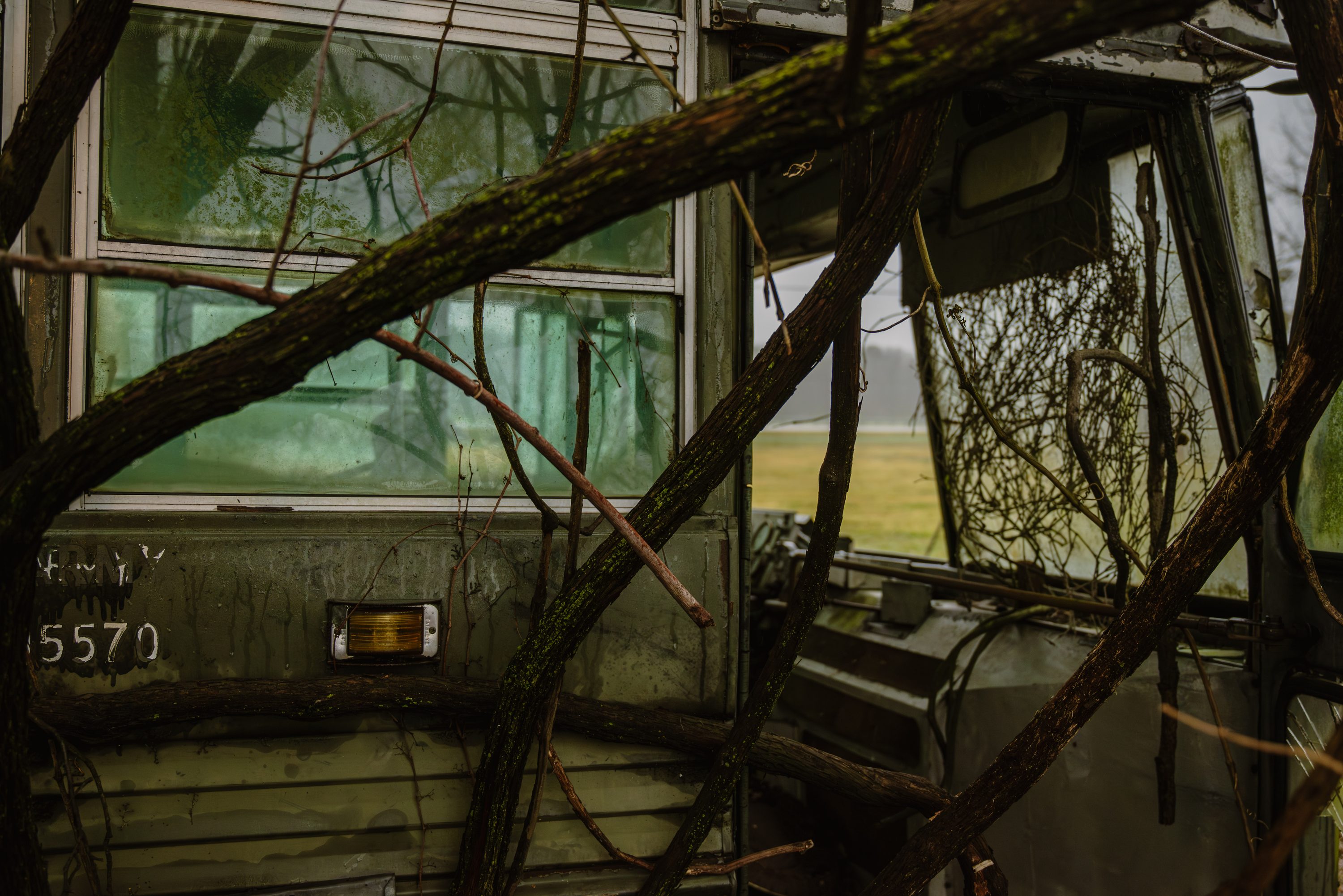 A damaged school bus sits abandoned in a field.