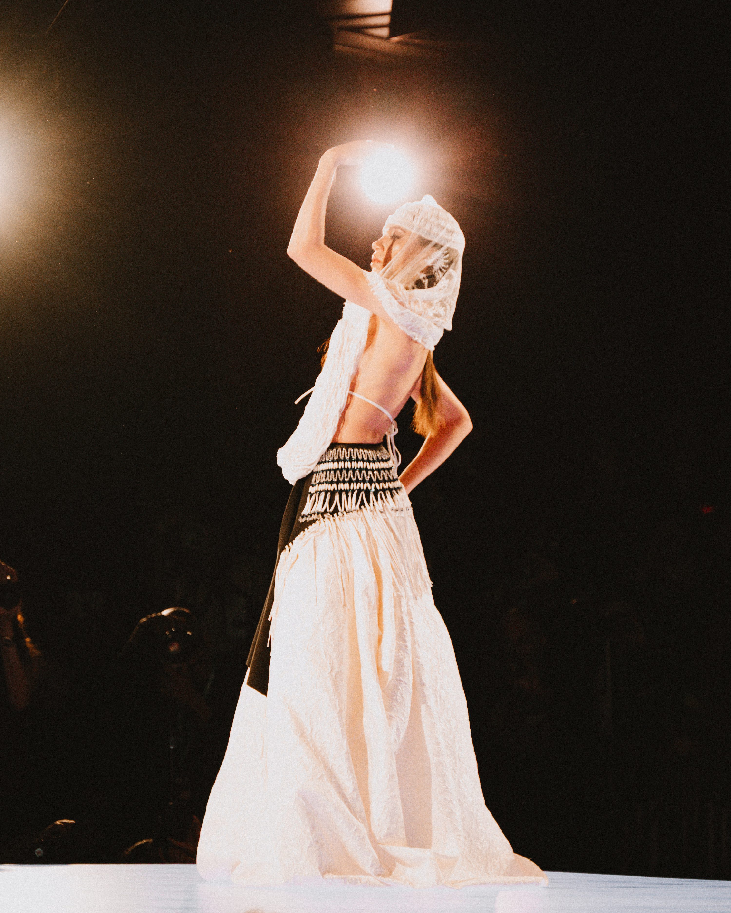 A model walks the runway in front of a seated audience.