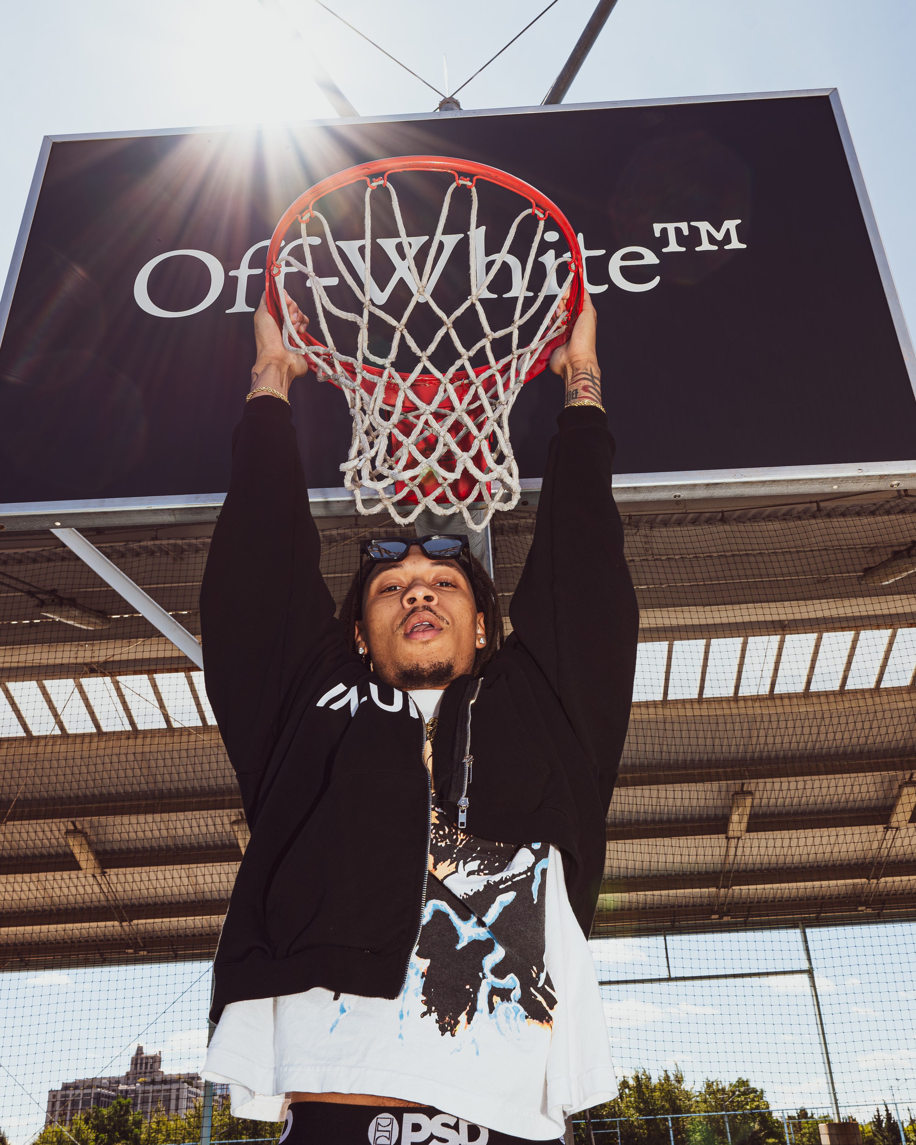 A player dunks beneath an Off-White backboard as sunlight flares behind the hoop.