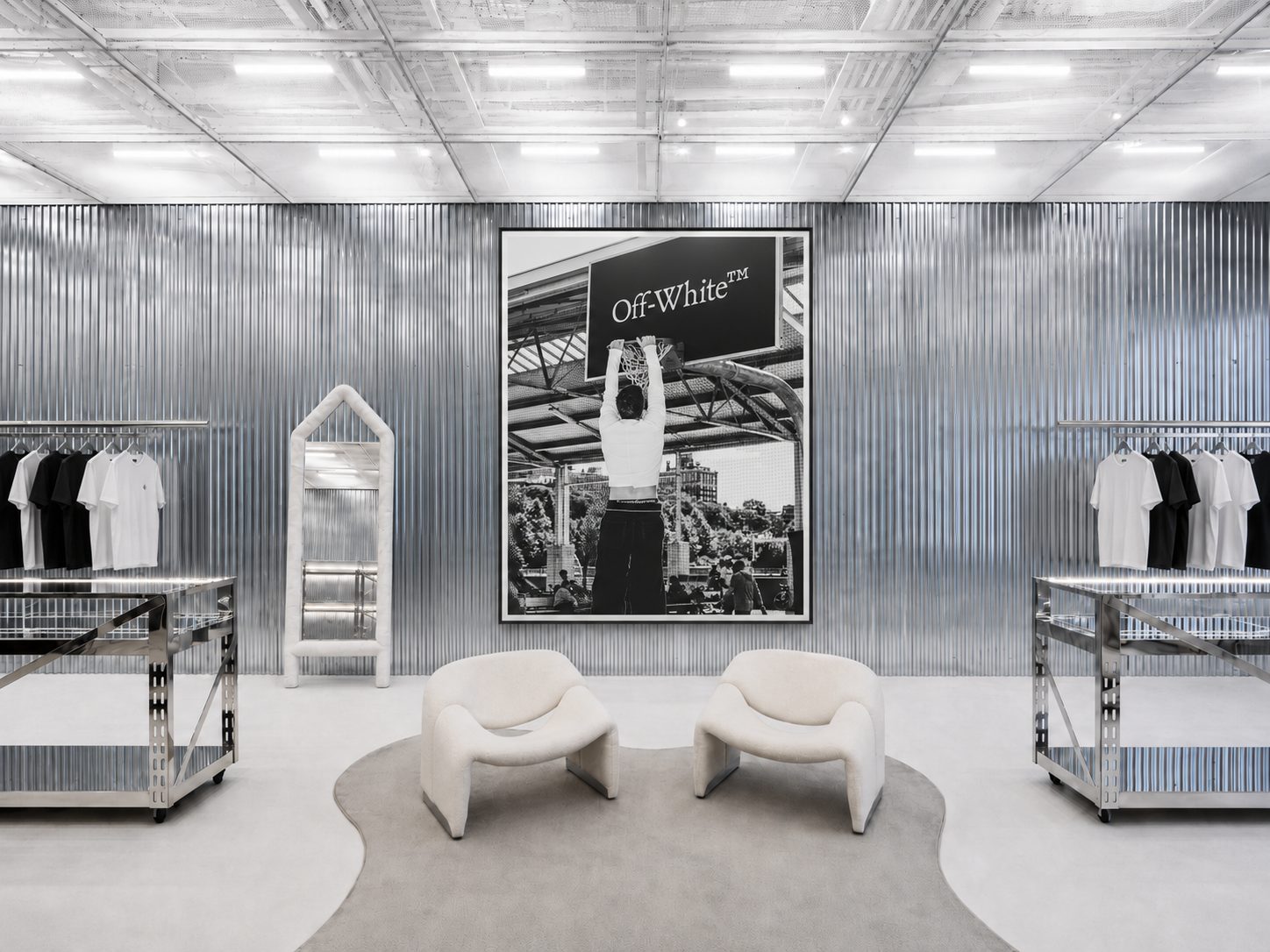 An Off-White store interior in monochrome: corrugated steel walls, two sculpted chairs, and a large basketball photograph.
