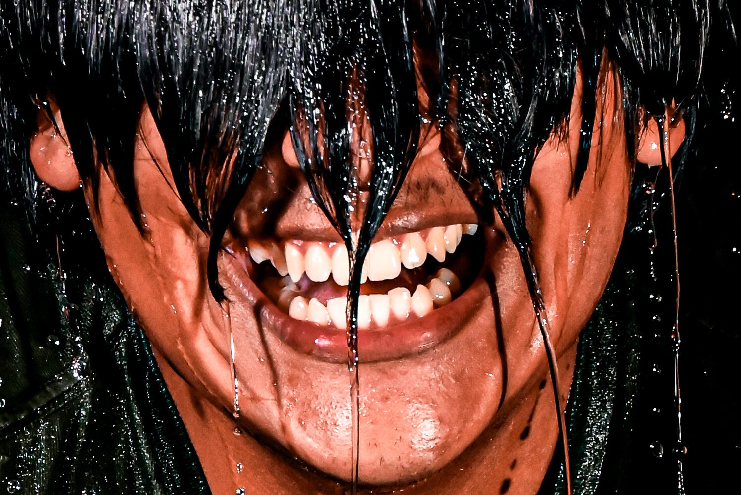 Water crashes over a person mid ice-bucket pour, caught by flash.