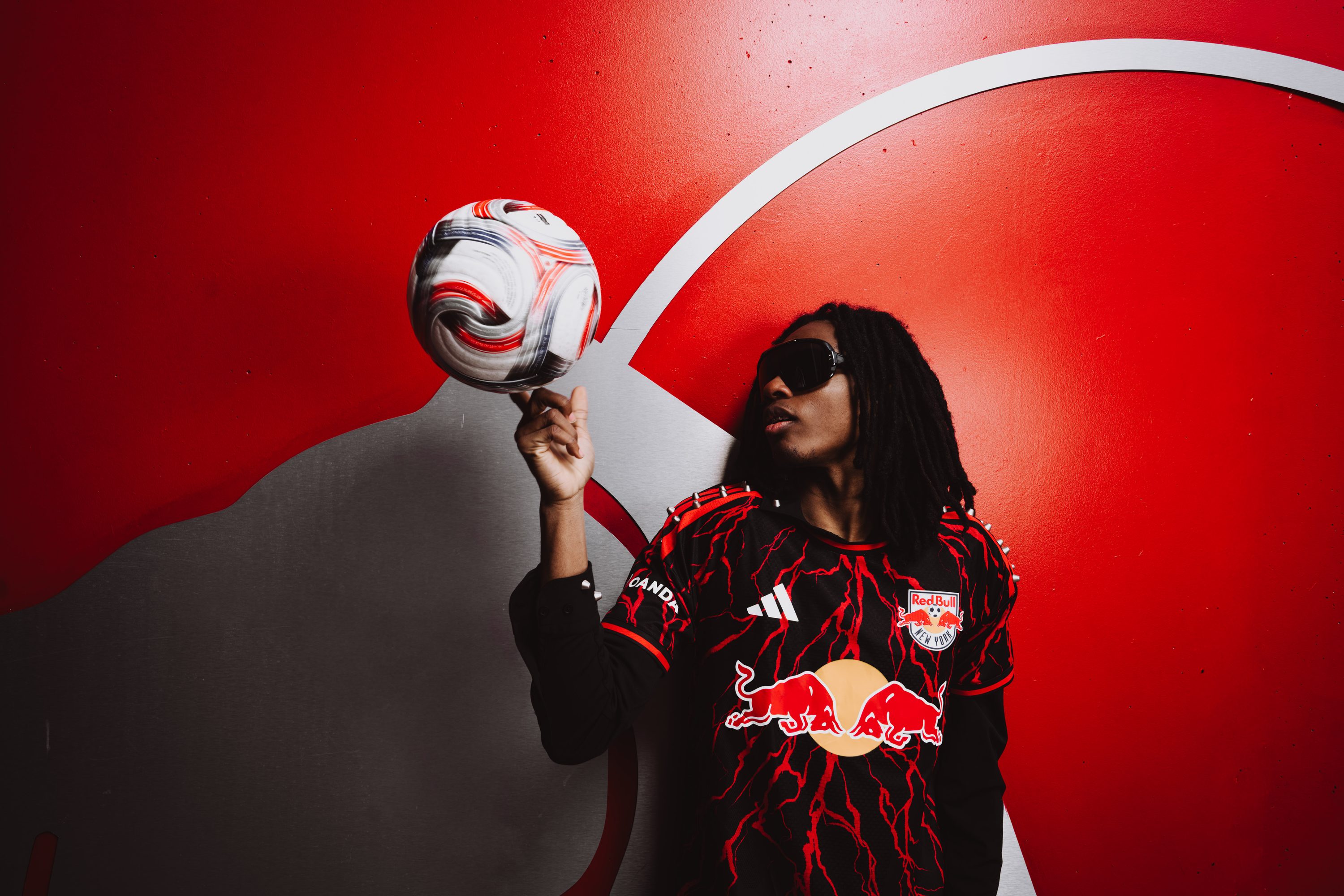 A model leans on a railing in Red Bull kit inside the stadium.