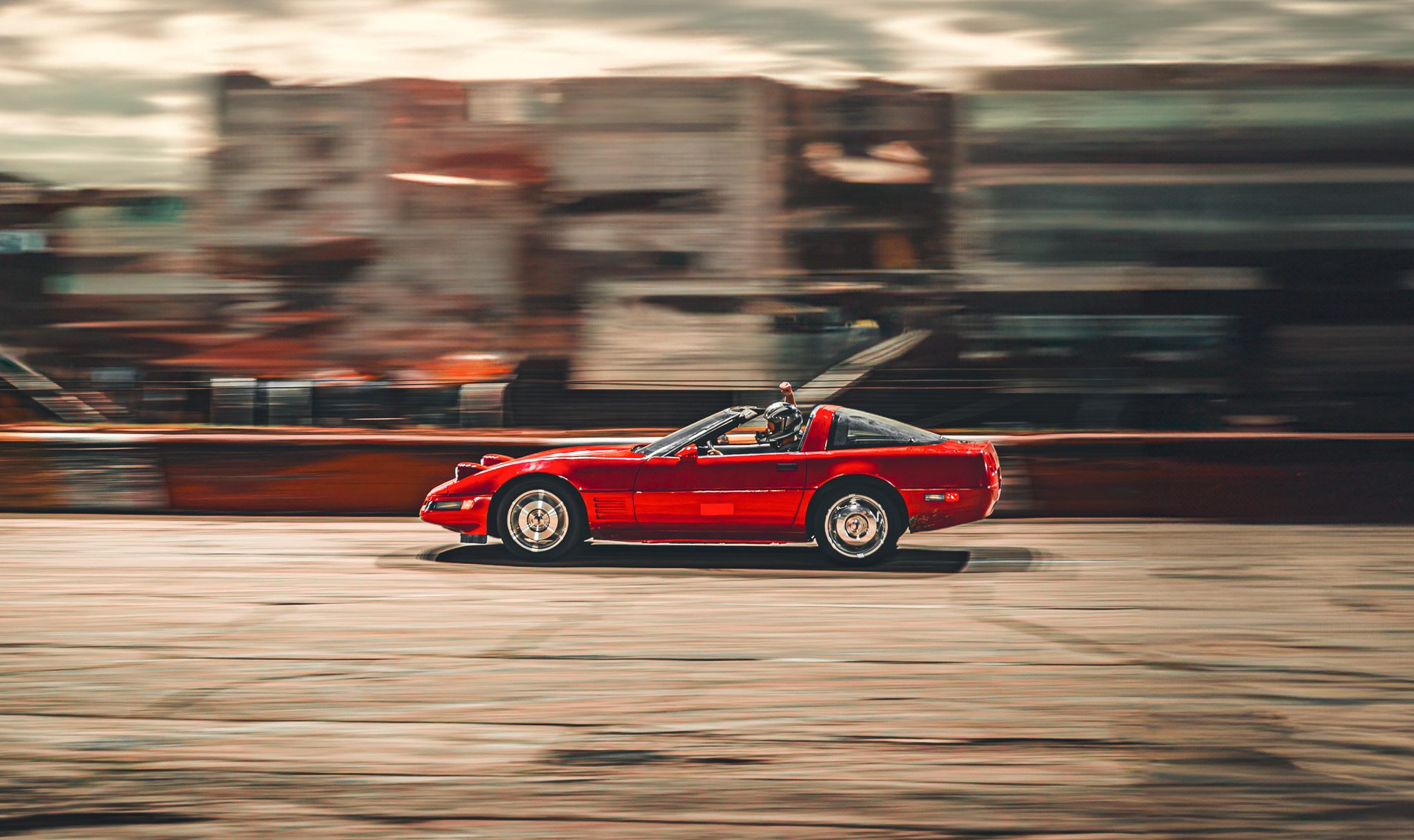 A red Corvette streaks past in a long panning blur.