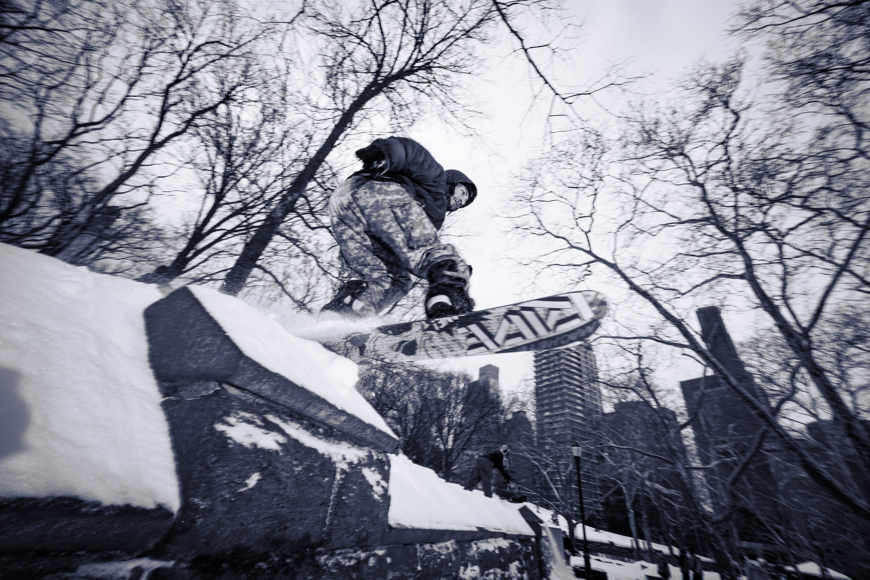 A snowboarder rides a rail above the Snow Jam crowd at night.